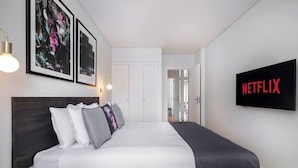 Une chambre à coucher avec un lit, une télévision et des tableaux encadrés accrochés au mur.