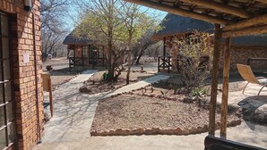 A courtyard with a brick building, a wooden pergola, and a stone pathway. - elephant memories safari lodge (marloth park)