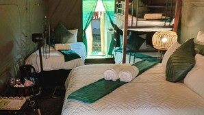 A tented room with two beds, a table with a basket, a chair, and a hanging light fixture. - elephant memories safari lodge (marloth park)
