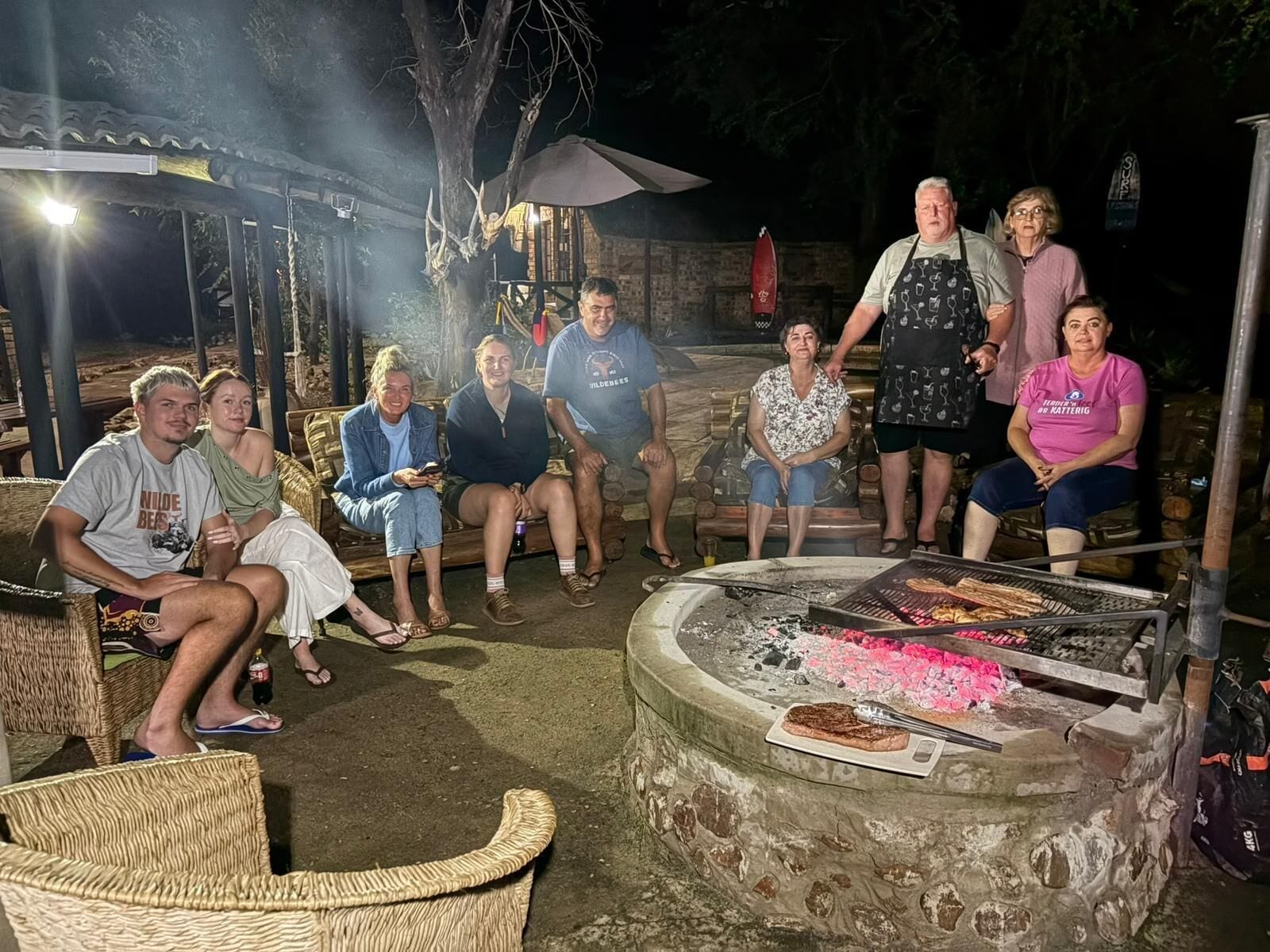 En grupp människor hade samlats runt en utomhusgrill där mat tillagades.