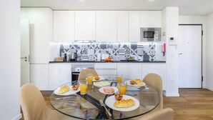 A modern kitchen with white cabinets, a microwave, and a patterned backsplash. - Alcântara Premium 2-bed | Wi-Fi | Lx Factory (Lisboa)