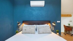 A bedroom with a large bed, two bedside lamps, a desk, and a chair.