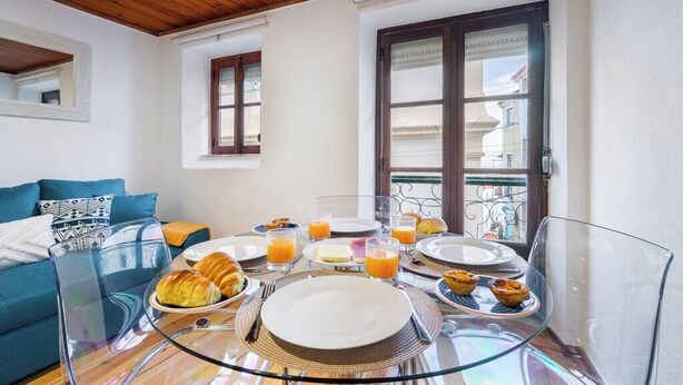 Een ontbijt opstelling met borden, glazen en croissants op een glazen tafel in een kamer met een houten plafond en uitzicht op een balkon.
