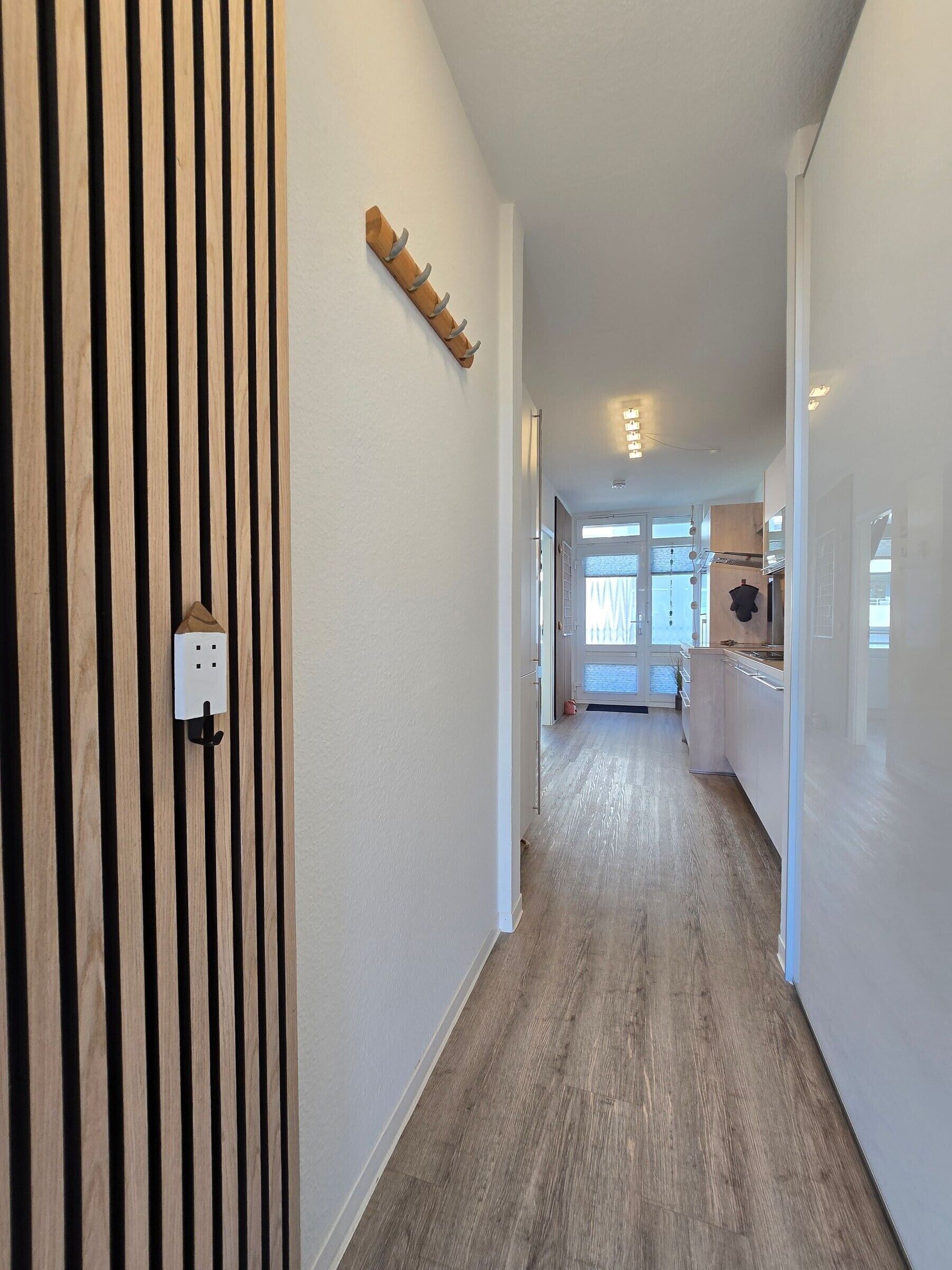 Ein Flur mit einer Wand aus Holzlatten, einem Kleiderständer und einer Steckdose.