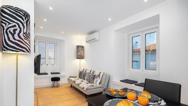 A modern living room with a sofa, a dining table with breakfast, and a TV.