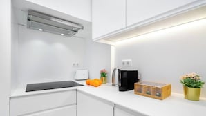 A modern kitchen with white cabinetry, a black countertop, a coffee maker, a toaster, and a wooden box.