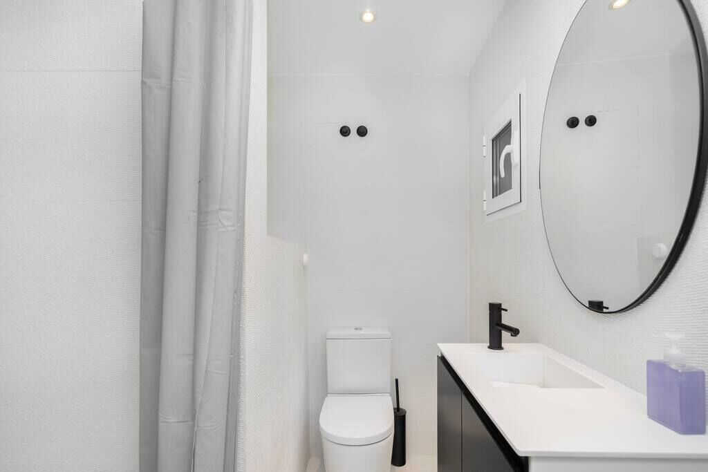 A modern bathroom with a white toilet, a black faucet, and a white sink.