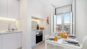 A modern kitchen with white cabinetry, a built-in oven, and a dining area with a table set for breakfast.