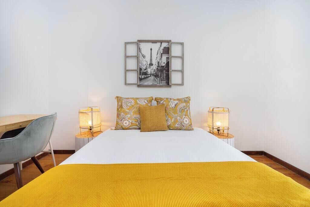 Une chambre d’hôtel avec un lit, deux lampes de chevet, une chaise et un tableau encadré au mur.