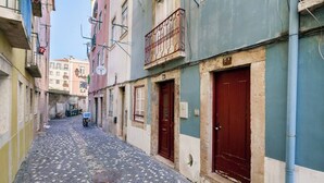 Uma rua de paralelepípedos estreita, ladeada por edifícios com varandas e portas.