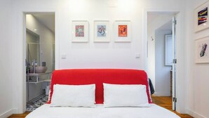A bedroom with a red headboard, white bedding, and three framed artworks on the wall. - Paz 2 | Tram28 | Wi-Fi | AC | Bairro Alto (Lisboa)