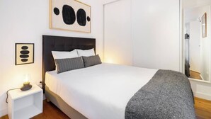 A bedroom with a bed, bedside table, and a wall-mounted artwork. - Paz 2 | Tram28 | Wi-Fi | AC | Bairro Alto (Lisboa)