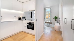 Eine moderne Küche mit weißen Schränken, einer Mikrowelle, einem Backofen und einem Essbereich mit einer Pflanze.