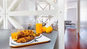 Ein Frühstücksangebot mit Croissants, Orangensaft und Zitronen auf einem Tablett.