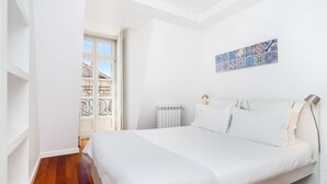 Ein Schlafzimmer mit Bett, Heizkörper, Fenster mit Blick und Wandbild.