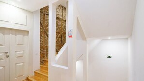 Eine Treppe führt zu einem Raum mit einer Steinwand und einer weißen Tür.