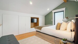 Ein modernes Schlafzimmer mit Bett, Sofa, Schreibtisch und Kleiderschrank.