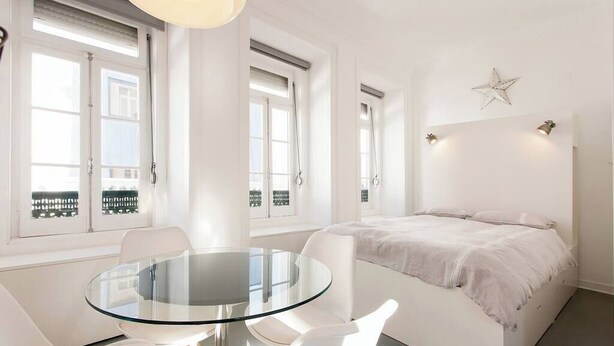Quarto moderno com mesa de vidro, móveis brancos e cama com decoração de estrela na parede.