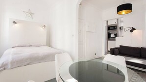 Quarto moderno e minimalista com mesa de jantar de vidro, mobiliário branco e uma decoração com tema de estrelas na parede.