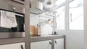 Cozinha moderna com armários brancos, exaustor de aço inoxidável e janela que ilumina naturalmente.