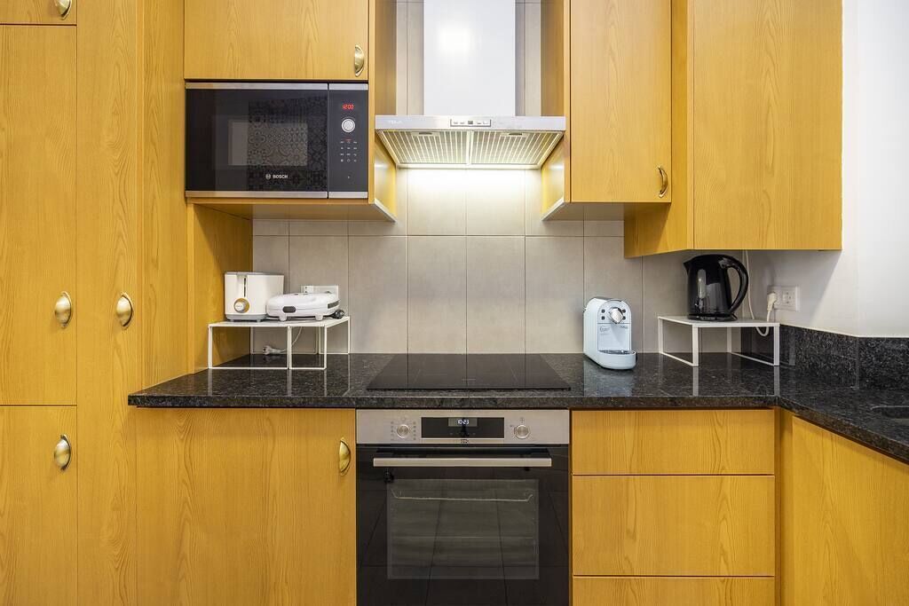 A modern kitchen with wooden cabinets, a Bosch microwave, a built-in oven, and a coffee maker.
