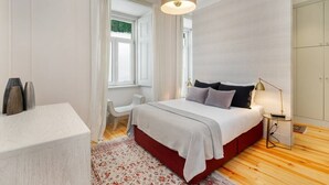 Ein modernes Schlafzimmer mit Bett, Nachttisch und einem Fenster mit Vorhängen.