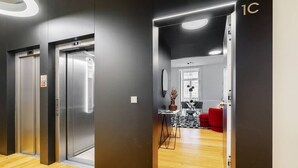 A modern elevator area with a wooden floor and a dining area with a table and chairs.