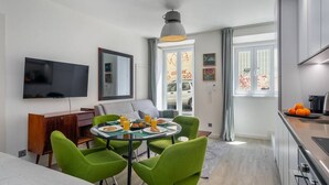 A modern living room with a dining area, a flat-screen TV, and a kitchen with a stove. - Lisbon Prime Aparts - Anjos (Lisboa)