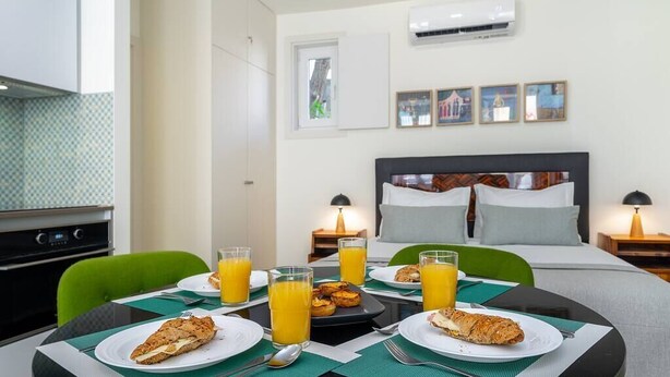 A hotel room with a dining table set for breakfast, a bed with a dark headboard, and a window with a view. - Lisbon Prime Aparts - Anjos (Lisboa)
