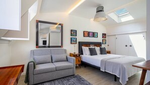 Ein modernes Schlafzimmer mit Sofa, Bett, Schreibtisch und Bildern an den Wänden.