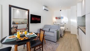 Ein kompakter Wohnbereich mit Essplatz, Küchenzeile und grauem Sofa.