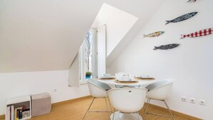 A modern dining area with a high ceiling, a skylight, and a wall decorated with fish decals. - Cozy Apartment in Lisbon’s Prime Area (Lisboa)
