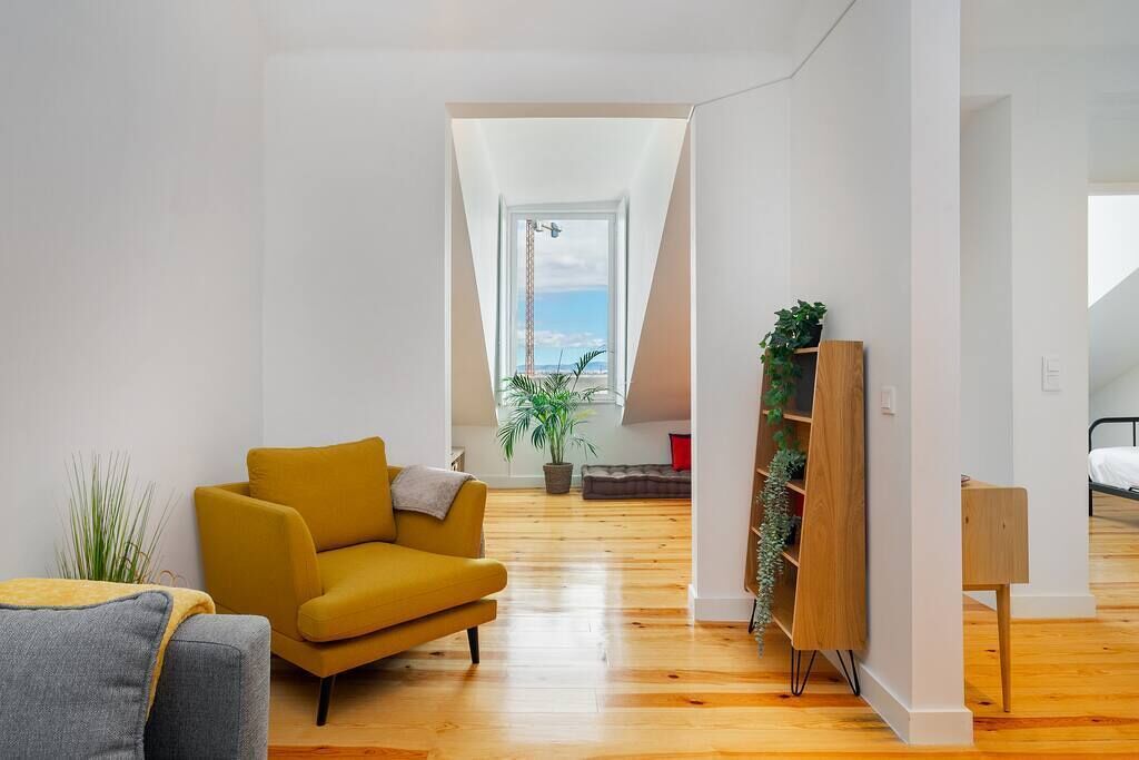 Un salon moderne avec un canapé jaune, un fauteuil gris et une bibliothèque en bois.