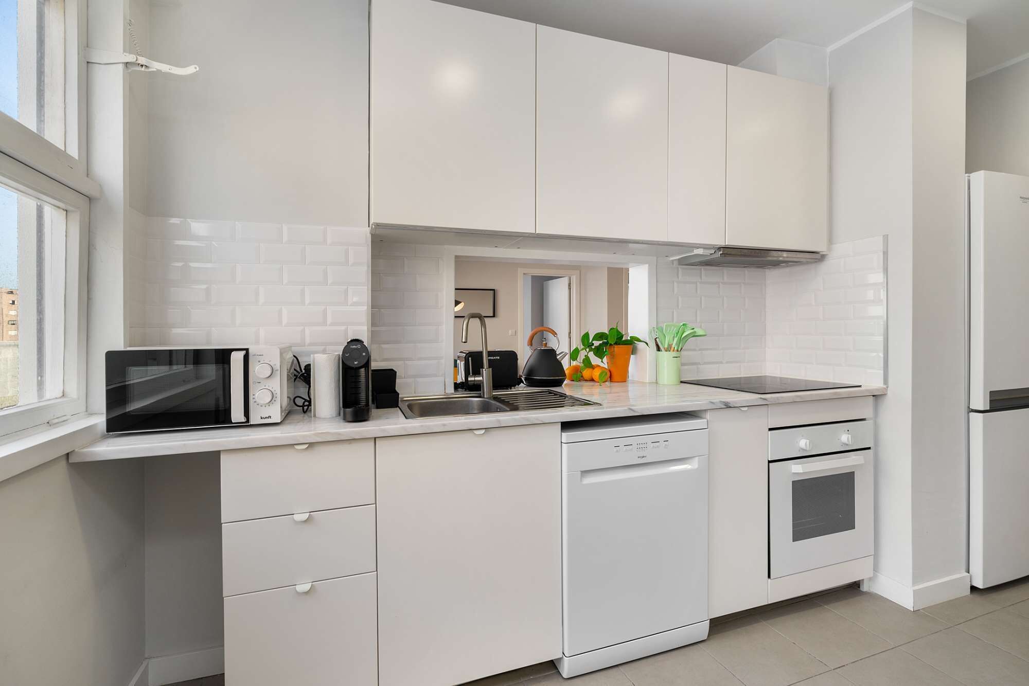 A modern kitchen with white cabinetry, a built-in dishwasher, a stove, and a refrigerator.