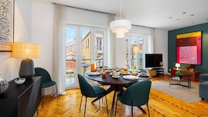 Ein modernes Wohnzimmer mit Essbereich, großen Fenstern und Blick auf die Stadt.