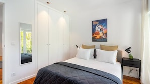 Ein Schlafzimmer mit Bett, Kleiderschrank, Nachttisch und einem Bild an der Wand.
