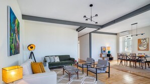 Un grand espace de vie comprenant un canapé, des fauteuils, une table basse et une table à manger avec des chaises.