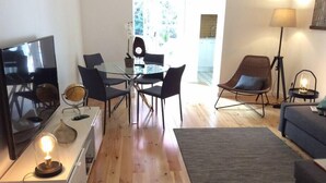 Een moderne woonkamer met een glazen eettafel, een bank, een televisie en een lamp.