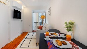 Une chambre d’hôtel comprenant un coin repas, un canapé, une télévision et une plante.