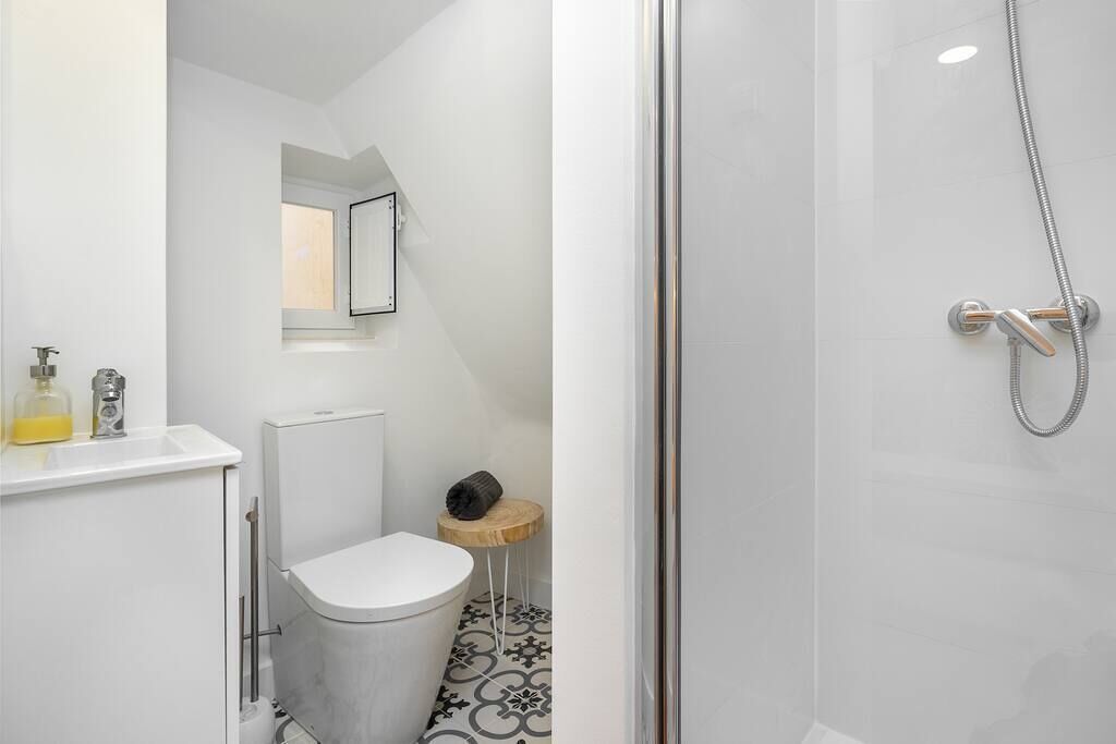 Un baño moderno con inodoro, una mesita con una toalla y una zona de ducha.