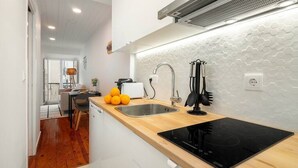 Une cuisine moderne dotée d’un plan de travail en bois, d’un évier en acier inoxydable et d’une plaque de cuisson à induction noire.