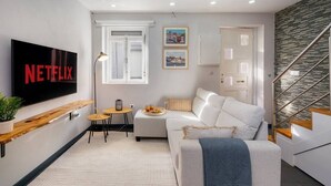 Een moderne woonkamer met een flatscreen televisie, een bank, een salontafel en een trap met een stenen muur.