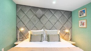 Een hotelkamer met een groot bed, een gestoffeerd hoofdbord, twee bedlampen en twee ingelijste foto's aan de muur.