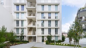 A modern multi-story residential building with balconies, a central staircase, and a well-maintained garden area. - City View Penthouse Luxurious Living in Lisbon (Lisboa)