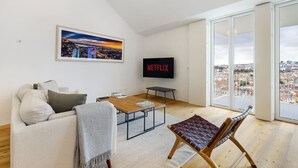 A modern living room with a sofa, coffee table, and a TV displaying 'NETFLIX'. - City View Penthouse Luxurious Living in Lisbon (Lisboa)