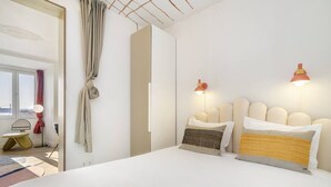 A modern hotel room with a large bed, two bedside lamps, and a view of the city through the window. - Historic Centre Modern Masterpiece w/ River Views (Lisboa)