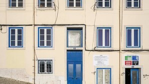 A multi-story building with a blue door and windows, a sign with text, and a cobblestone street. - Historic Centre Modern Masterpiece w/ River Views (Lisboa)