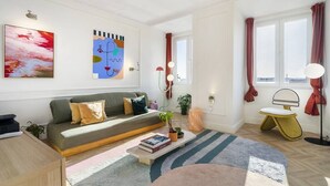 A modern living room with a sofa, a coffee table with books, a rug, and a small stool. - Historic Centre Modern Masterpiece w/ River Views (Lisboa)