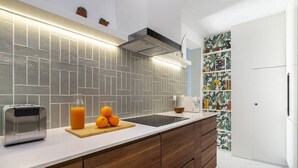 A modern kitchen with a white countertop, a toaster, a cutting board with oranges, and a backsplash with geometric tiles. - Historic Centre Modern Masterpiece w/ River Views (Lisboa)