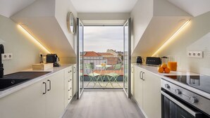 Ett modernt kök med en central köksö, en matplats med bord och stolar samt utsikt över stadsbilden genom stora fönster.